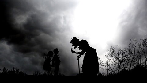 A silhouette of a witch and two kids at night