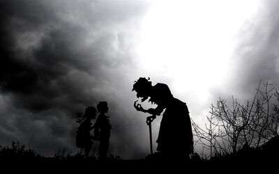 A silhouette of a witch and two kids at night
